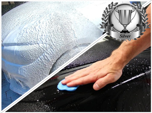 Een zwarte auto wordt met een blauwe doek afgeveegd, waarbij de gewaxte afwerking en het zilveren trofee-embleem zichtbaar zijn.