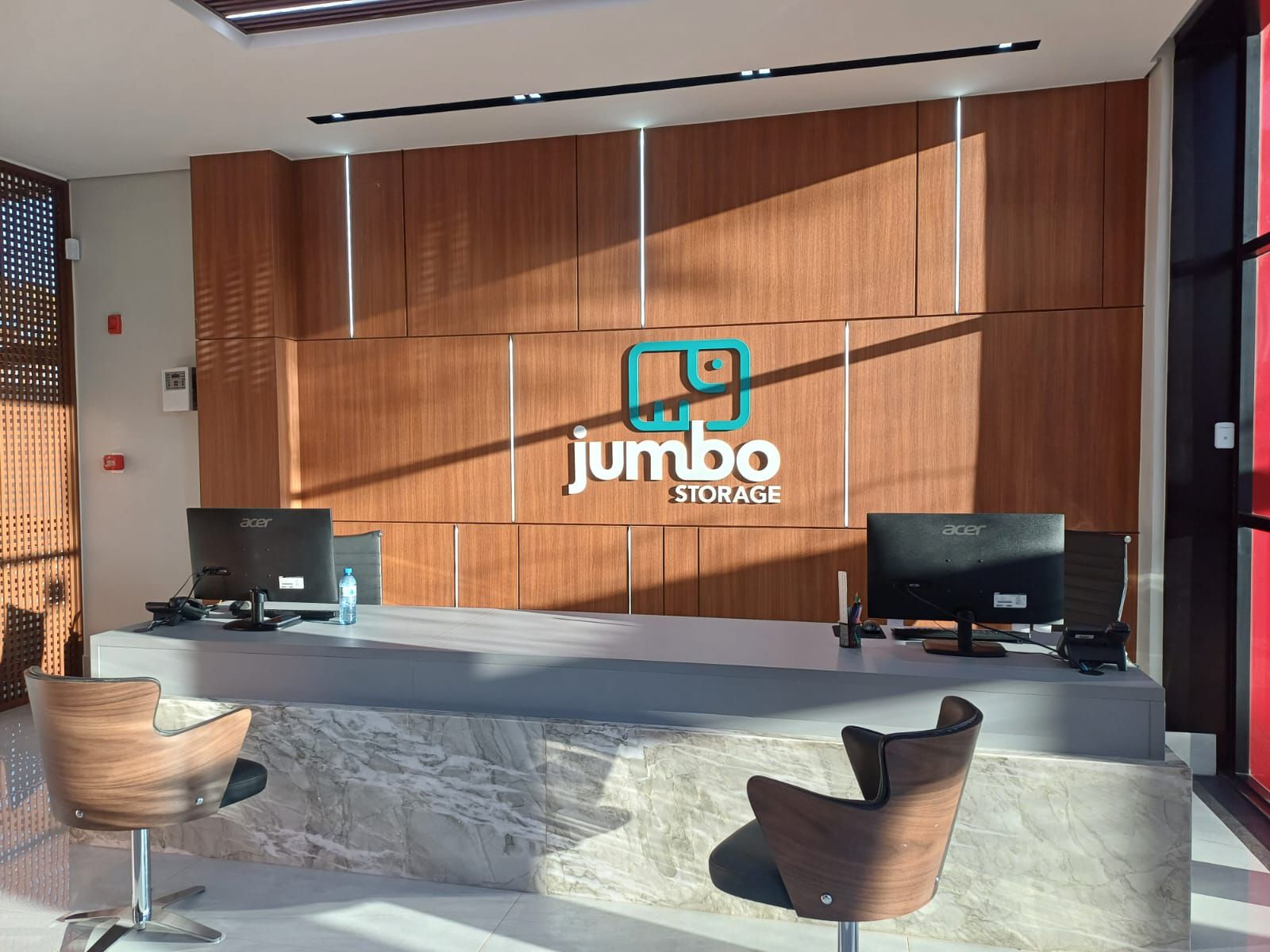 Uma recepção moderna com duas cadeiras, dois computadores e o logotipo 