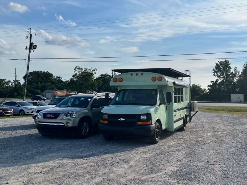 Two cars are parked next to each other in a gravel lot.