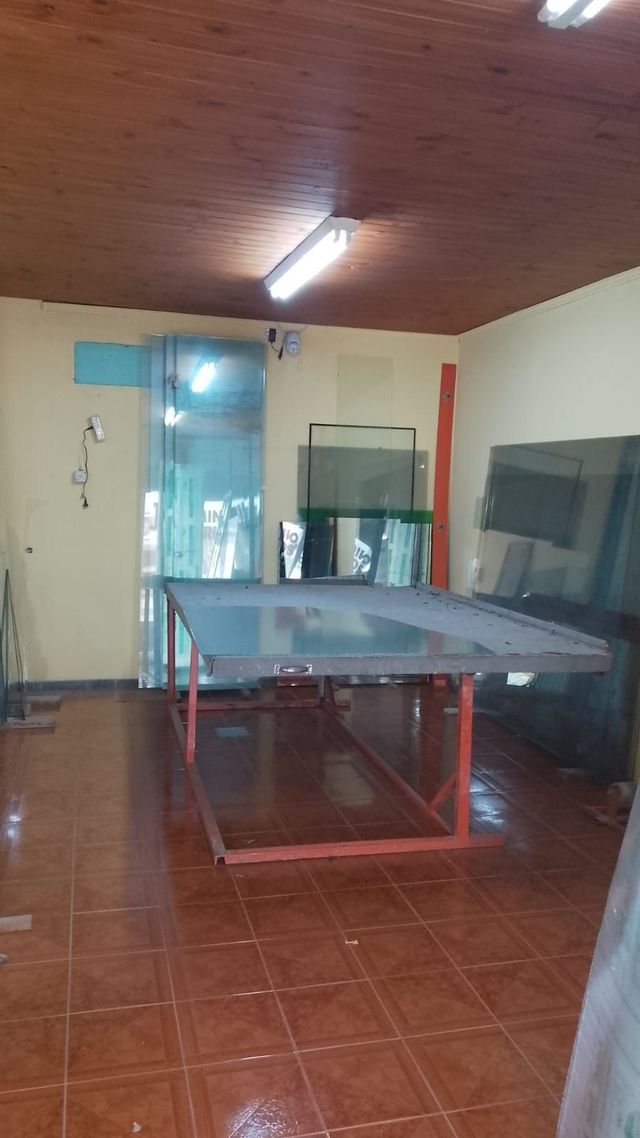 Habitación interior con una mesa de ping-pong azul, suelo de baldosas, techo de madera y un gran espejo en la pared.