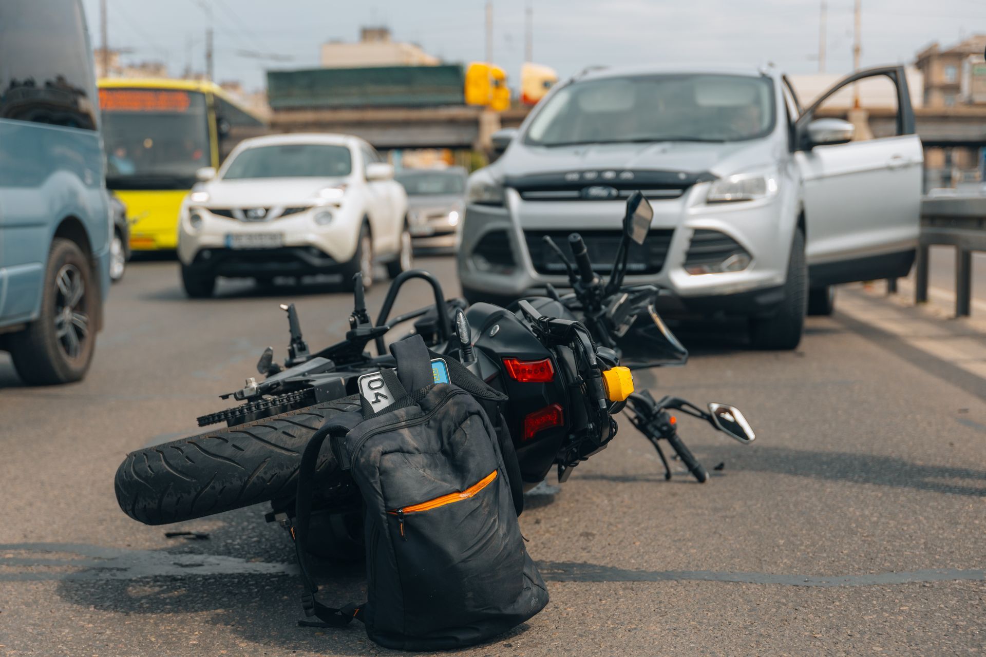 Damaged bicycle lying on a road after a crash, with cars stopped nearby.