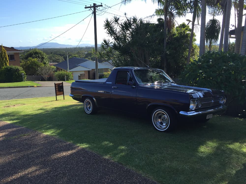 A Blue Pickup Truck Is Parked In The Grass In Front Of A House — All Port Smash Repairs in Laurieton, NSW