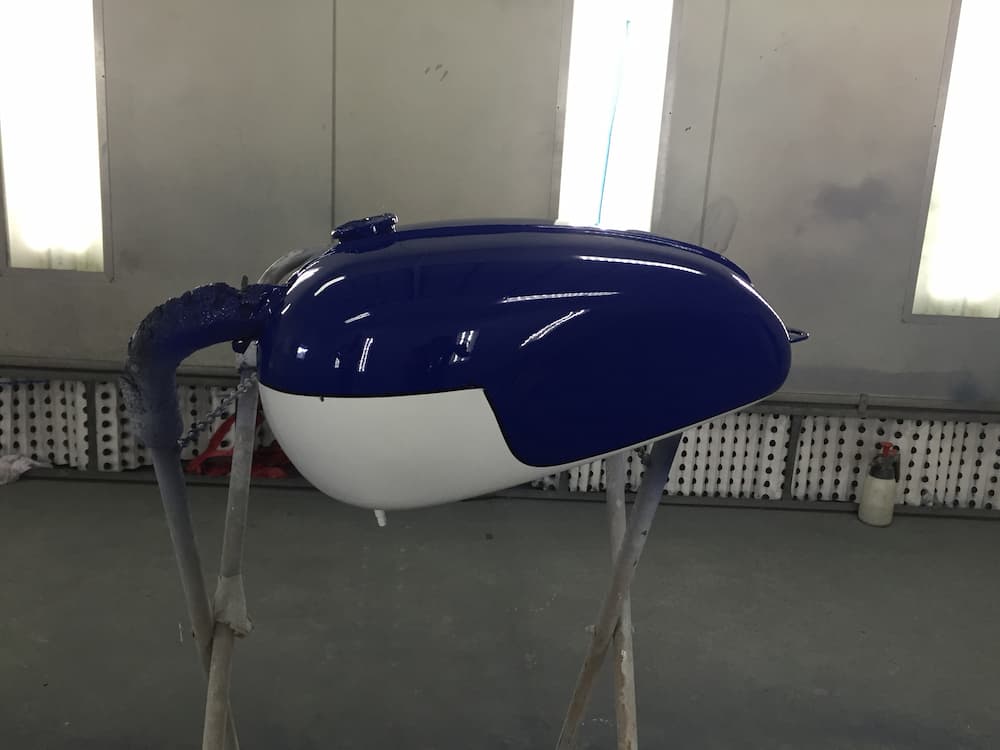 A Blue And White Motorcycle Tank Is Sitting On A Stand In A Paint Booth — All Port Smash Repairs in Laurieton, NSW