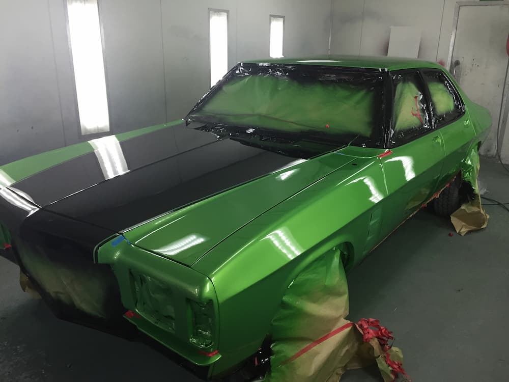 A Green Car Is Being Painted In A Paint Booth — All Port Smash Repairs in Port Macquarie, NSW