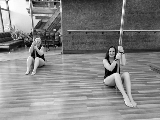 Two people sitting on swings on a wooden deck, smiling at the camera.