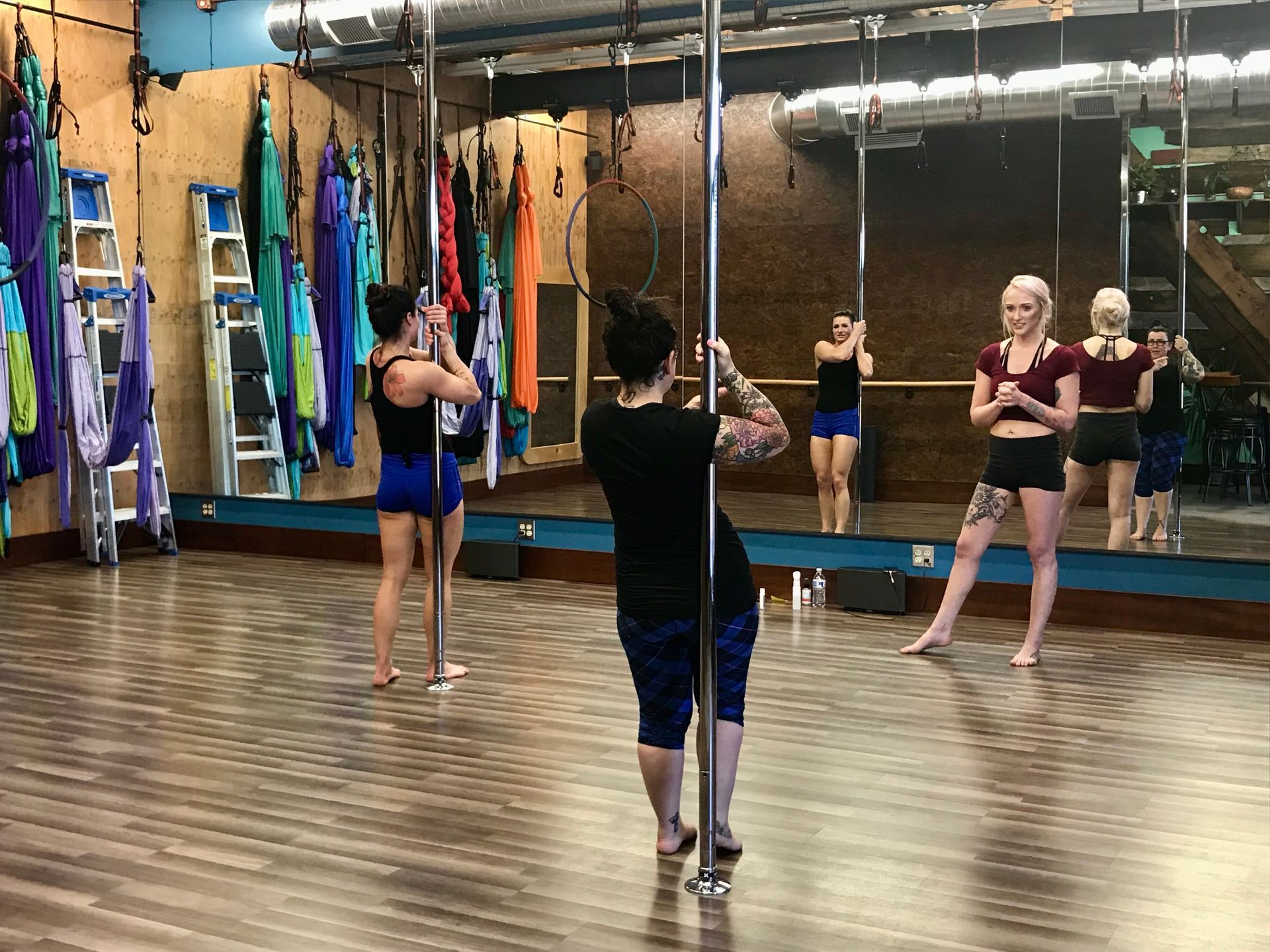 People practicing dance in a studio with mirrors and a wooden floor
