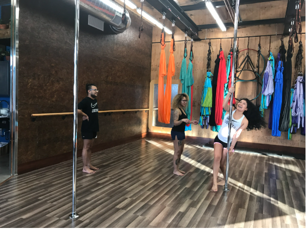 People practicing aerial yoga in a studio with hanging silks and poles