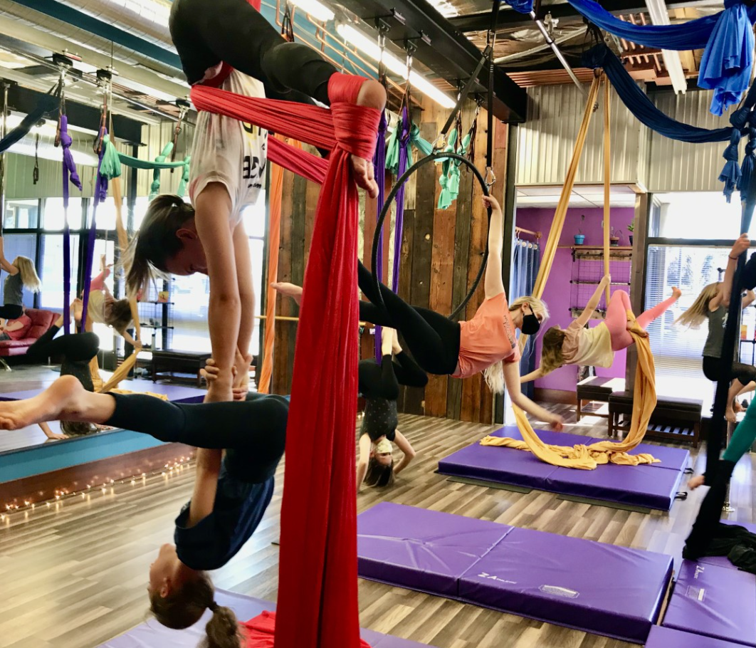 Aerial yoga class with people on fabric hammocks in a studio