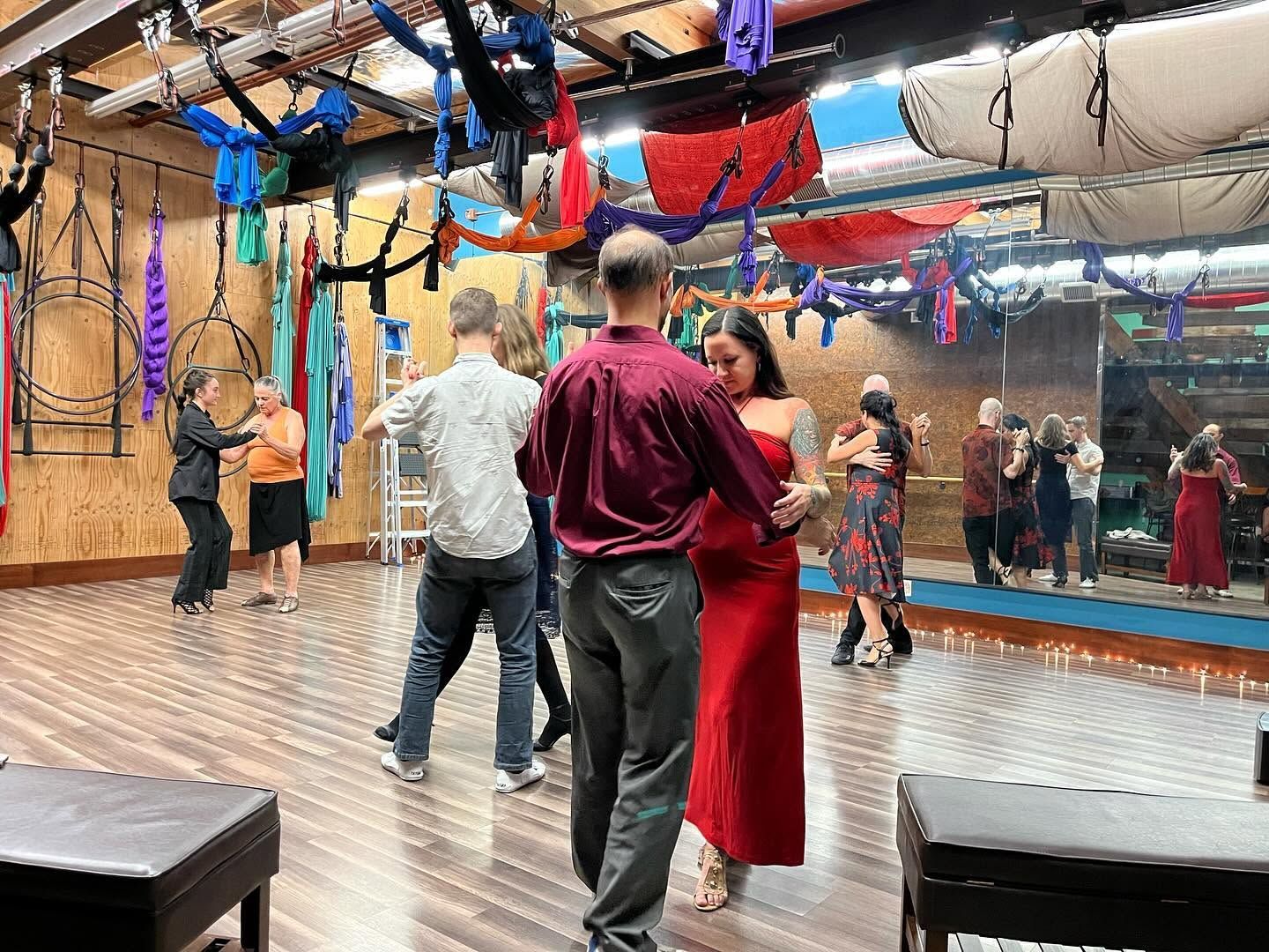 Couple ballroom dancing in a mirrored studio with colorful hanging ribbons and hardwood floors