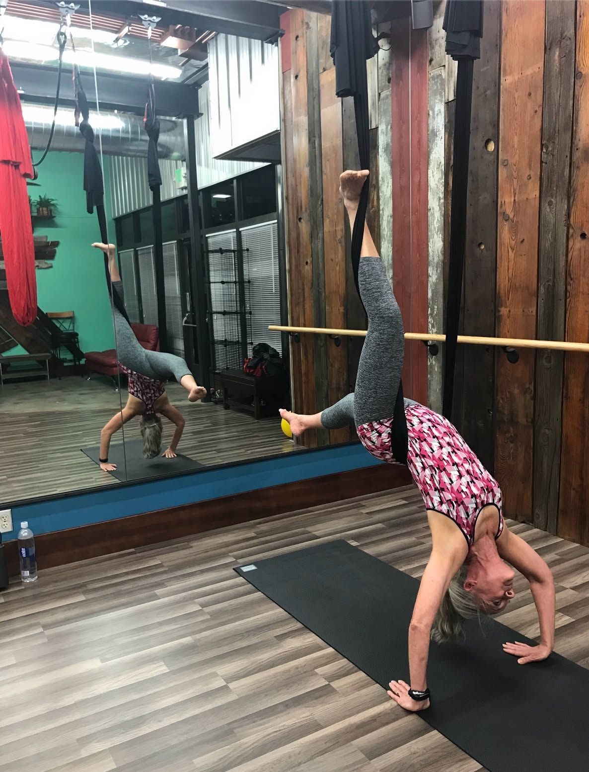 Person practicing a yoga handstand in a studio, reflected in a wall mirror.