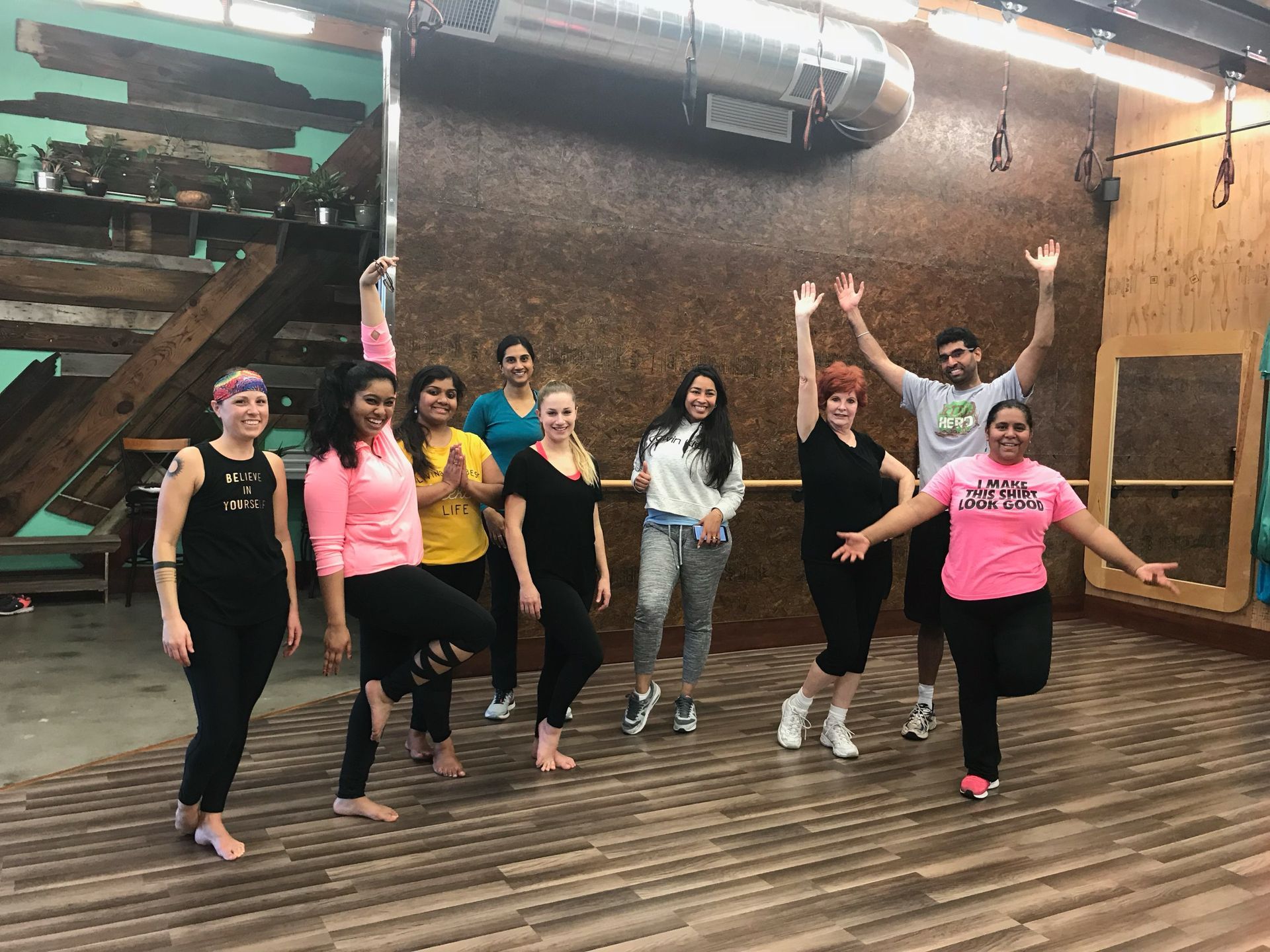 Group dancing in a studio with wood floors, brick wall, and mirrored background