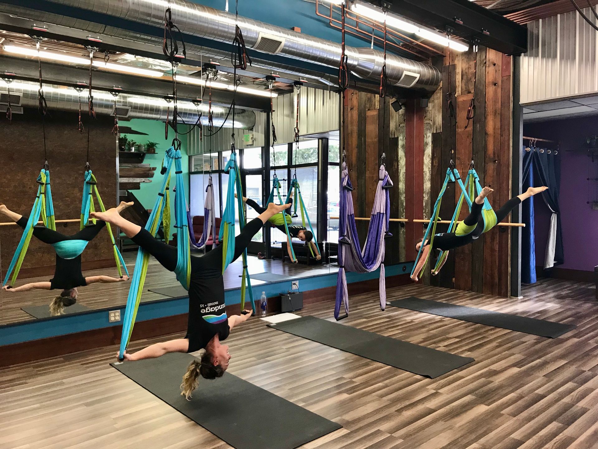 Person performing an aerial pose on a purple hoop in a studio setting