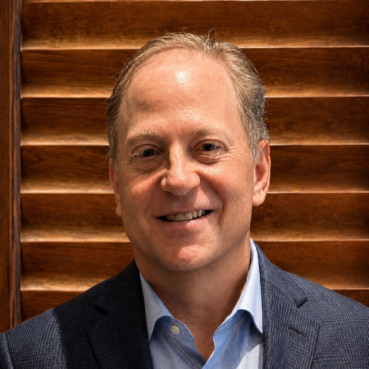 A man in a suit and white shirt is smiling for the camera.