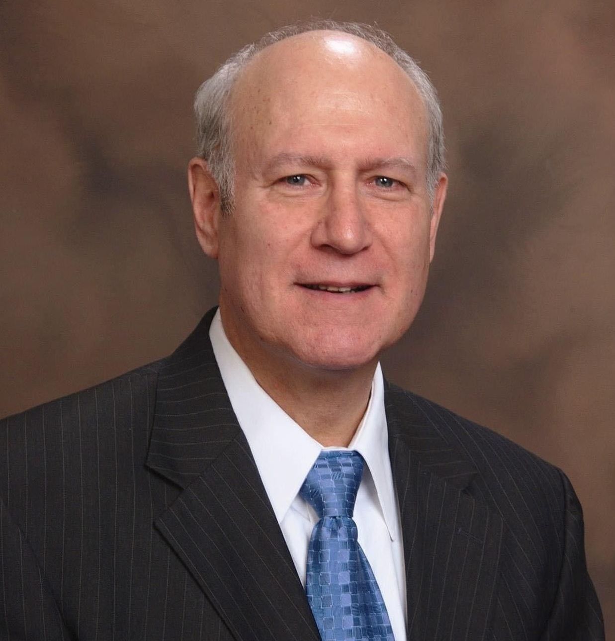A man in a suit and white shirt is smiling for the camera.