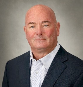 A man in a suit and white shirt is smiling for the camera.