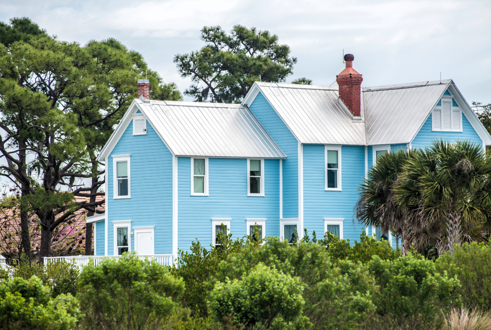 Picture of a two-story house with a grey metal roof installed on it.
