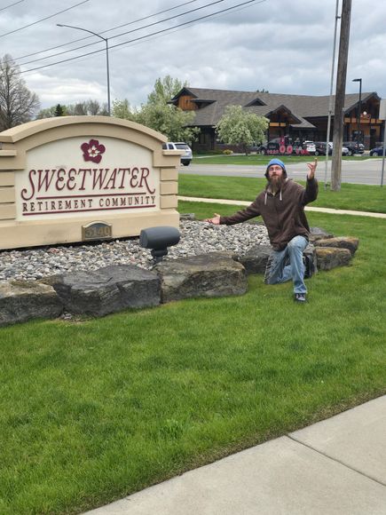 A man is kneeling in front of a sweetwater sign