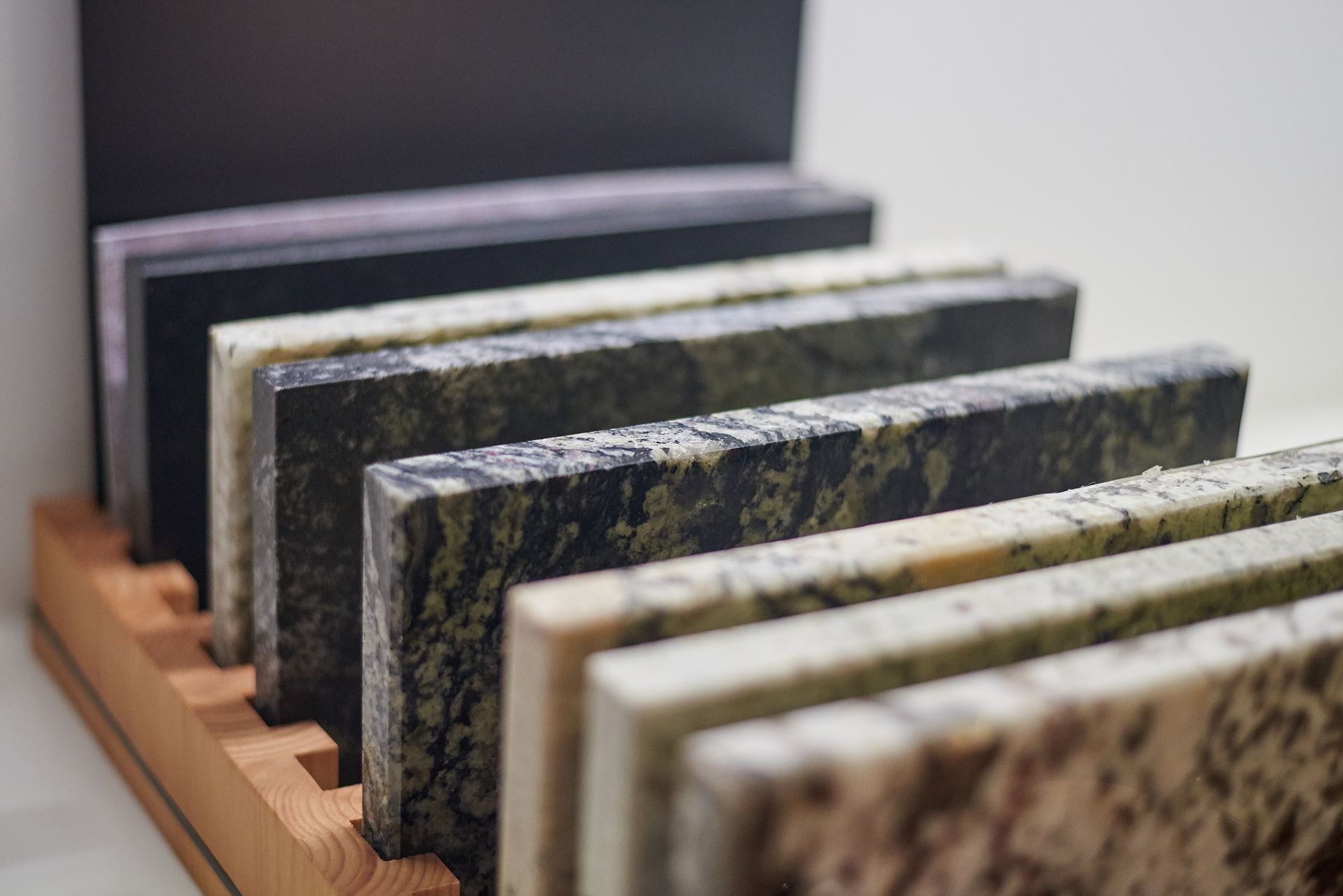 A wooden display case filled with different types of granite.
