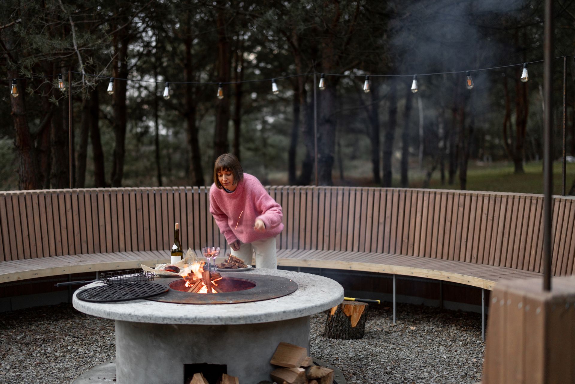 A woman is standing in front of a fire pit.