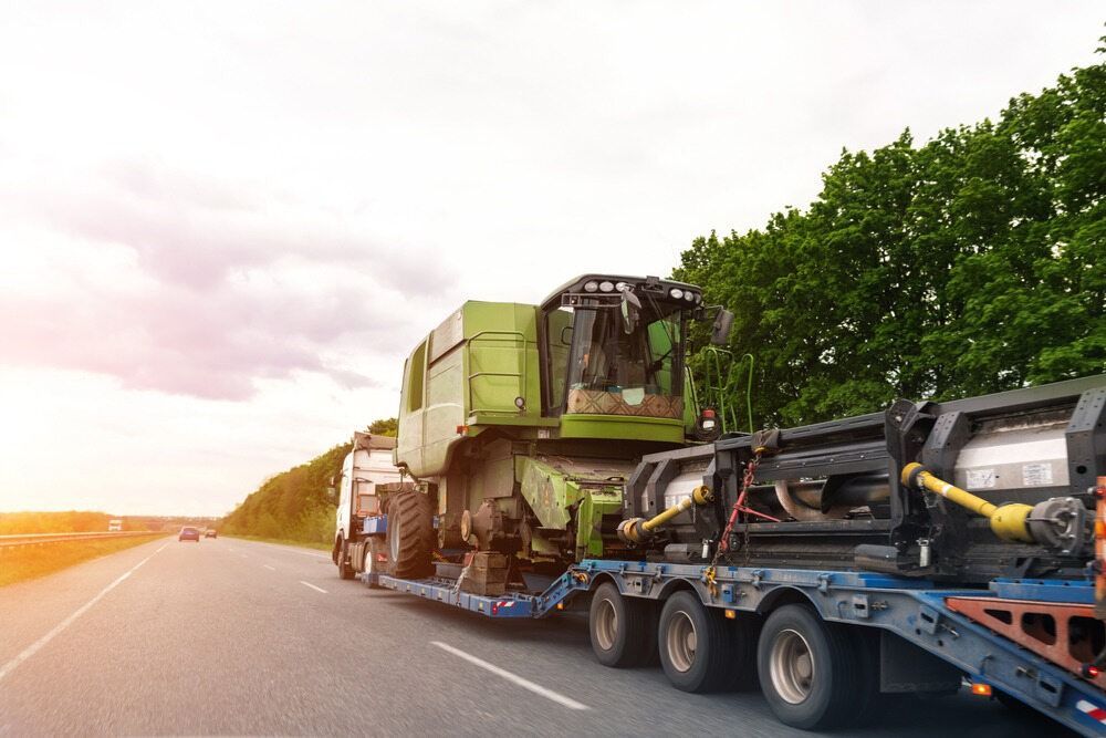 A Semi Truck Is Carrying A Combine Harvester Down A Highway — RJN Transport In Gunnedah, NSW
