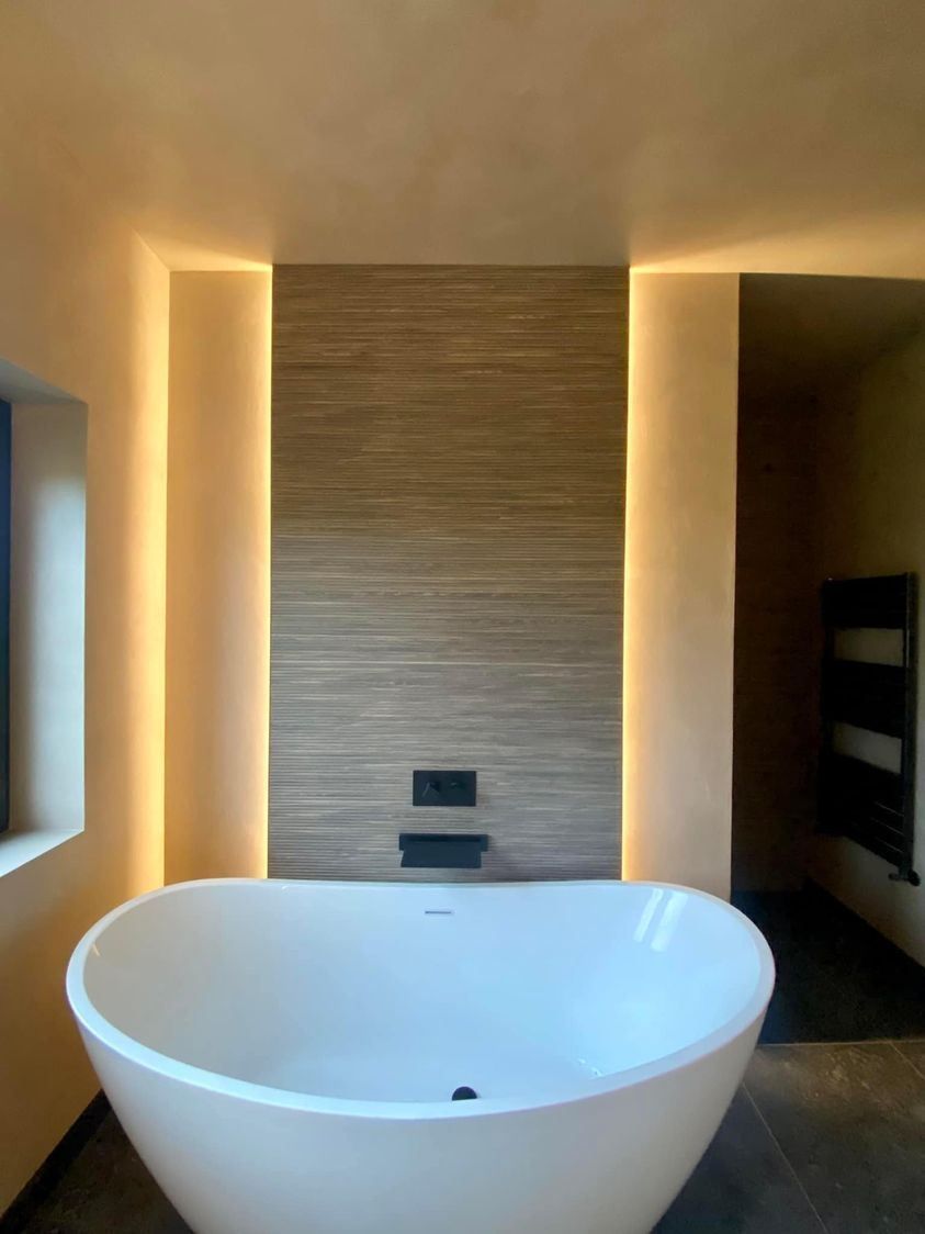 Una grande vasca da bagno bianca si trova in un bagno accanto a una finestra.