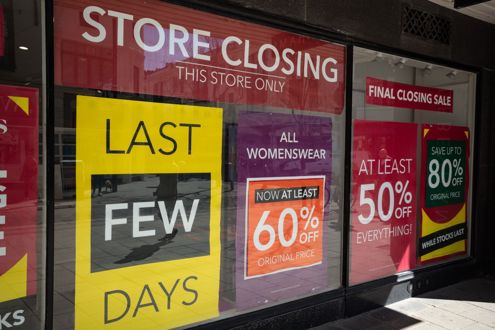 A store is closing and has a lot of signs on the window.