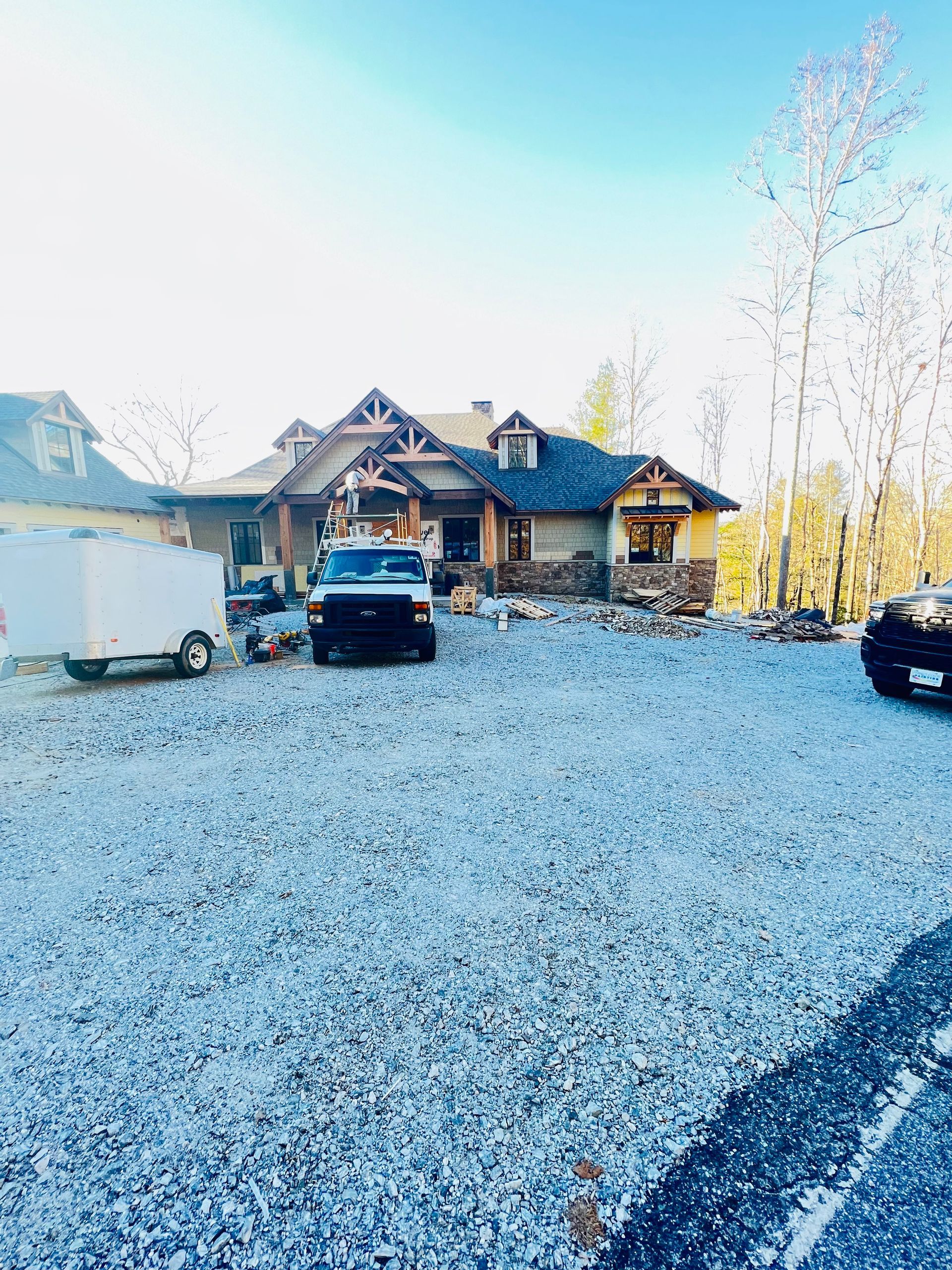 A jeep is parked in a gravel lot in front of a house.