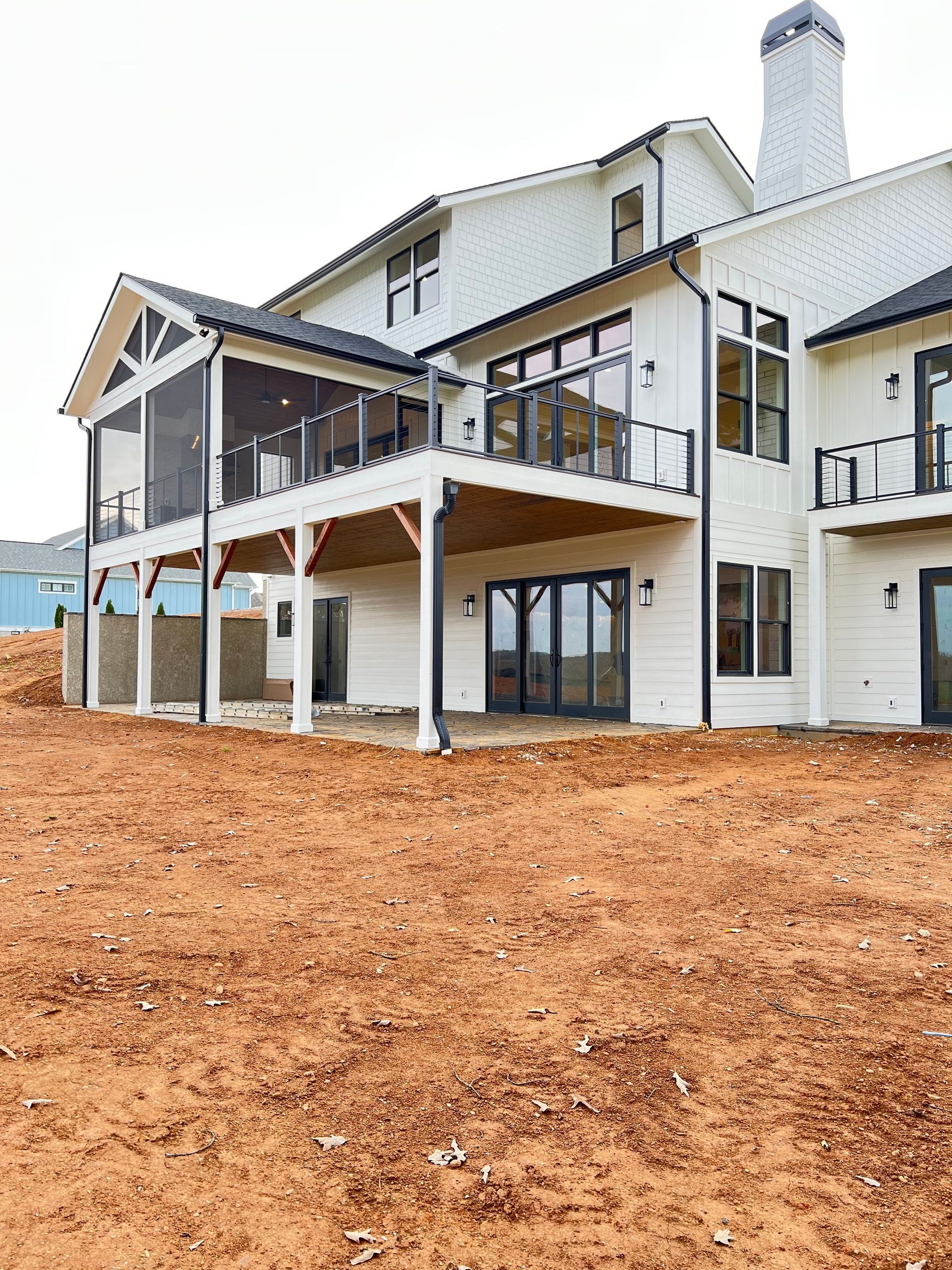 A large white house is sitting on top of a dirt field.