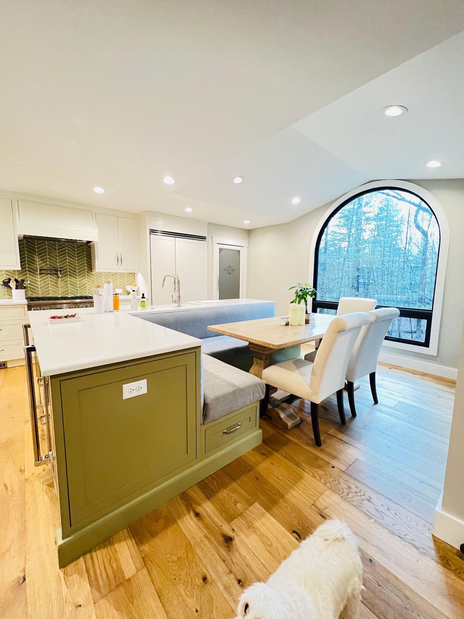 A kitchen with a table and chairs and a dog sitting on the floor.