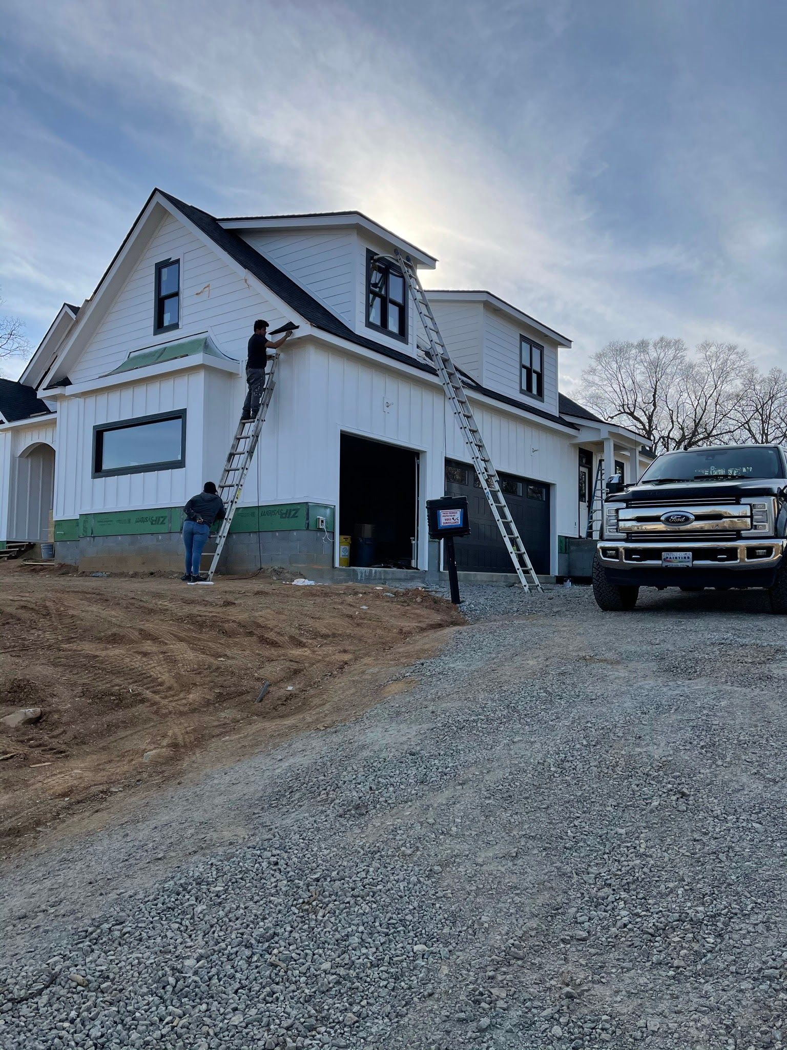 A white house under construction with a truck parked in front of it.