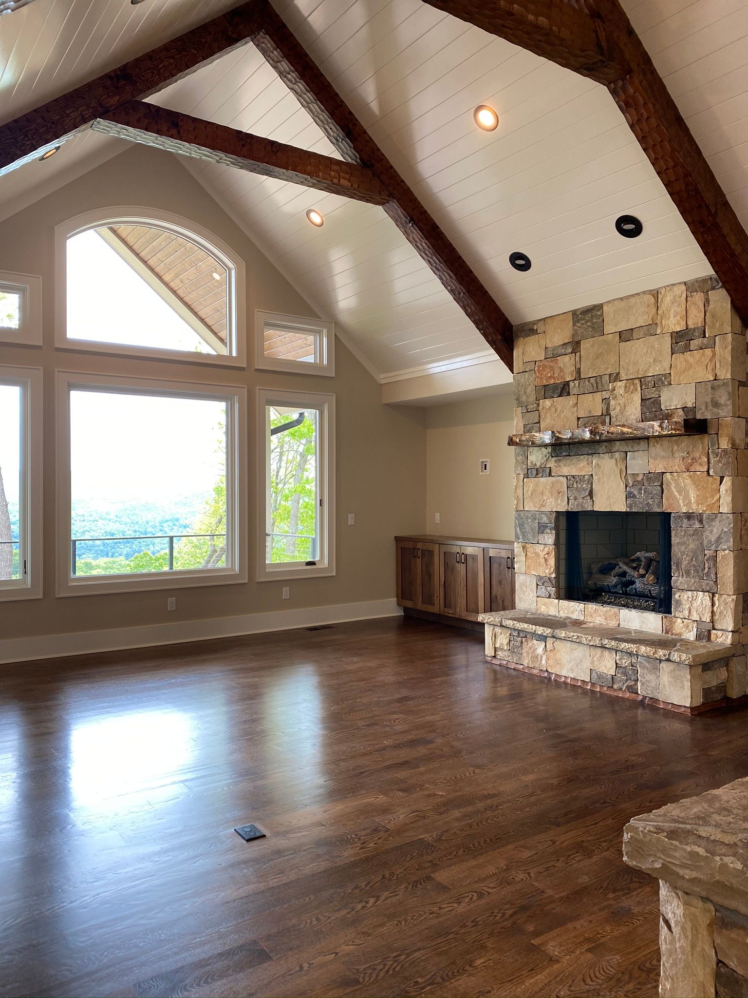 An empty living room with a fireplace and lots of windows.
