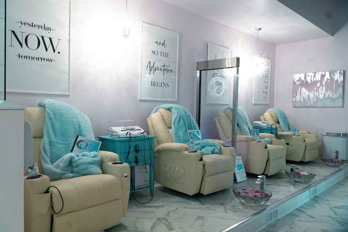 Salon interior with beige recliners, turquoise blankets, and inspirational posters.