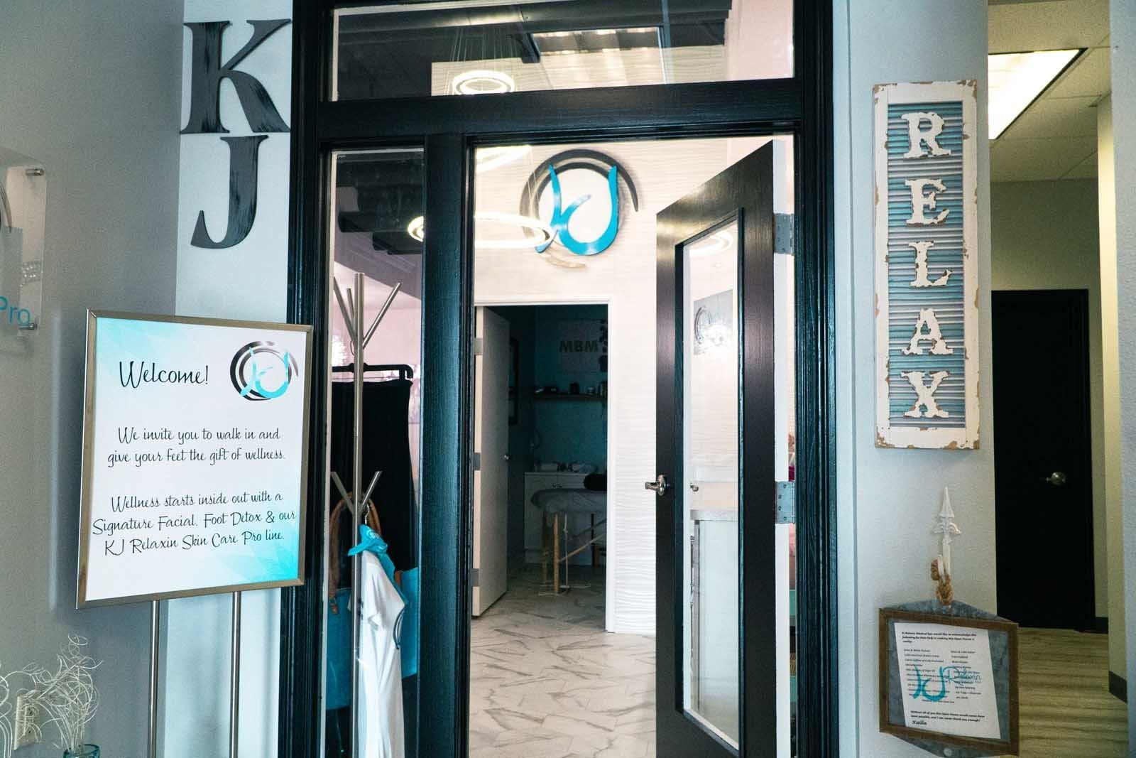 Entrance to a spa with black doors and a welcome sign. A 
