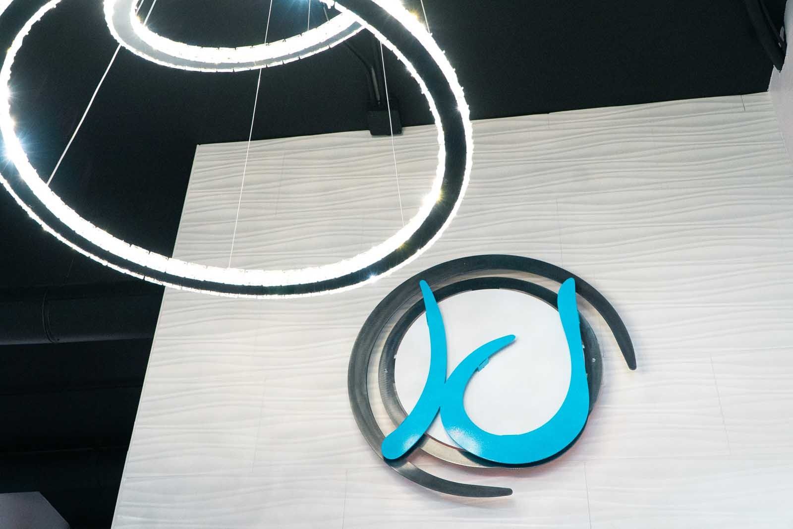 Light fixture above a wall with a teal and silver logo.