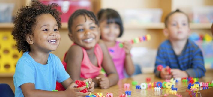 A group of children are sitting at a table playing with toys.