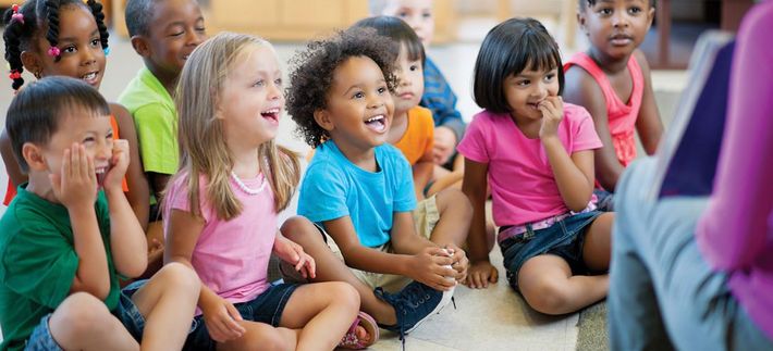 A group of children are sitting on the floor listening to a story.