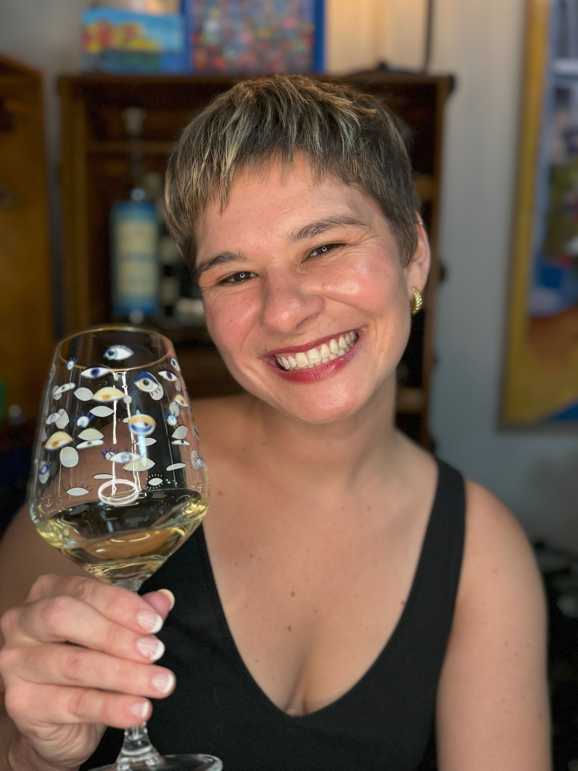 Co-owner of No Wine Left Behind, smiling and holding a glass of white wine 