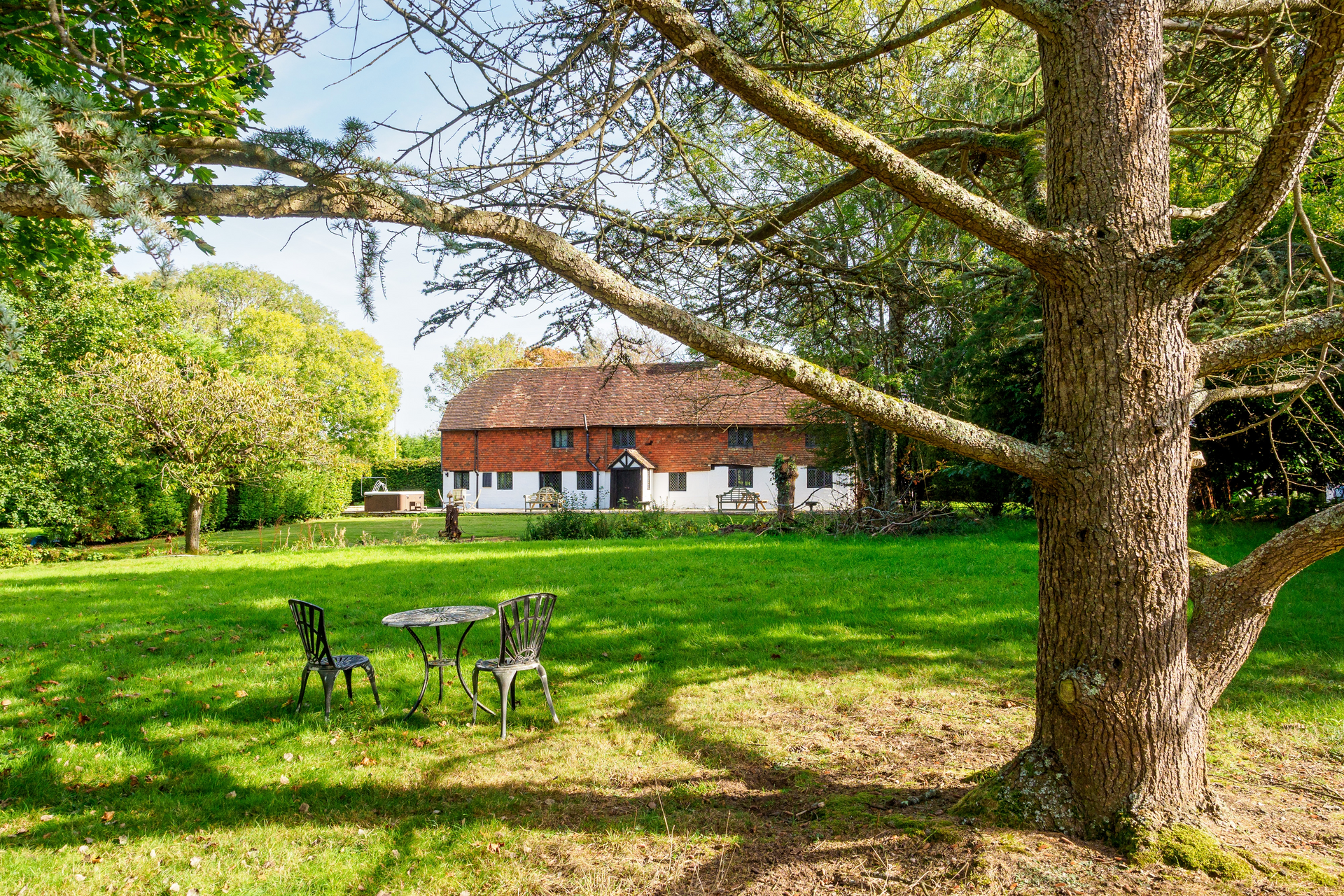 Brick house with green lawn and trees, with a wooden playset in the yard