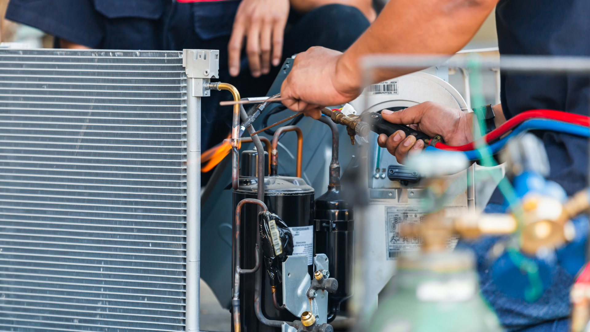 Technician repairing an air conditioner condenser with tools and refrigerant lines visible
