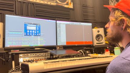 A man is sitting in front of a keyboard in a recording studio.