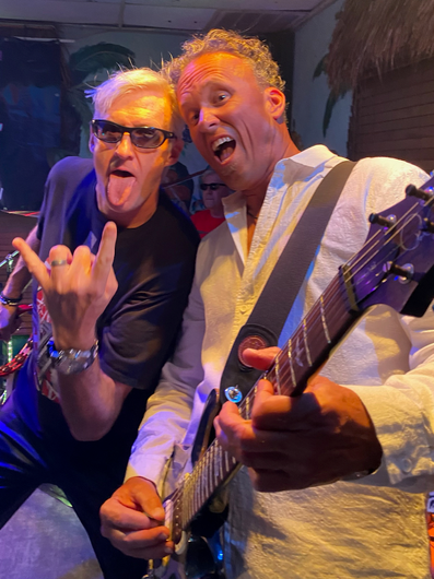 Two men are posing for a picture while one of them is playing a guitar.