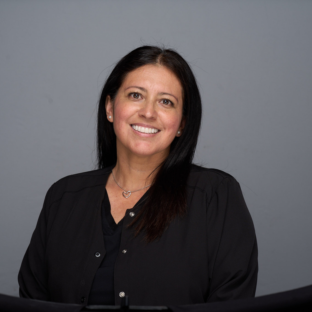 Smiling woman in a black blouse against a gray studio background