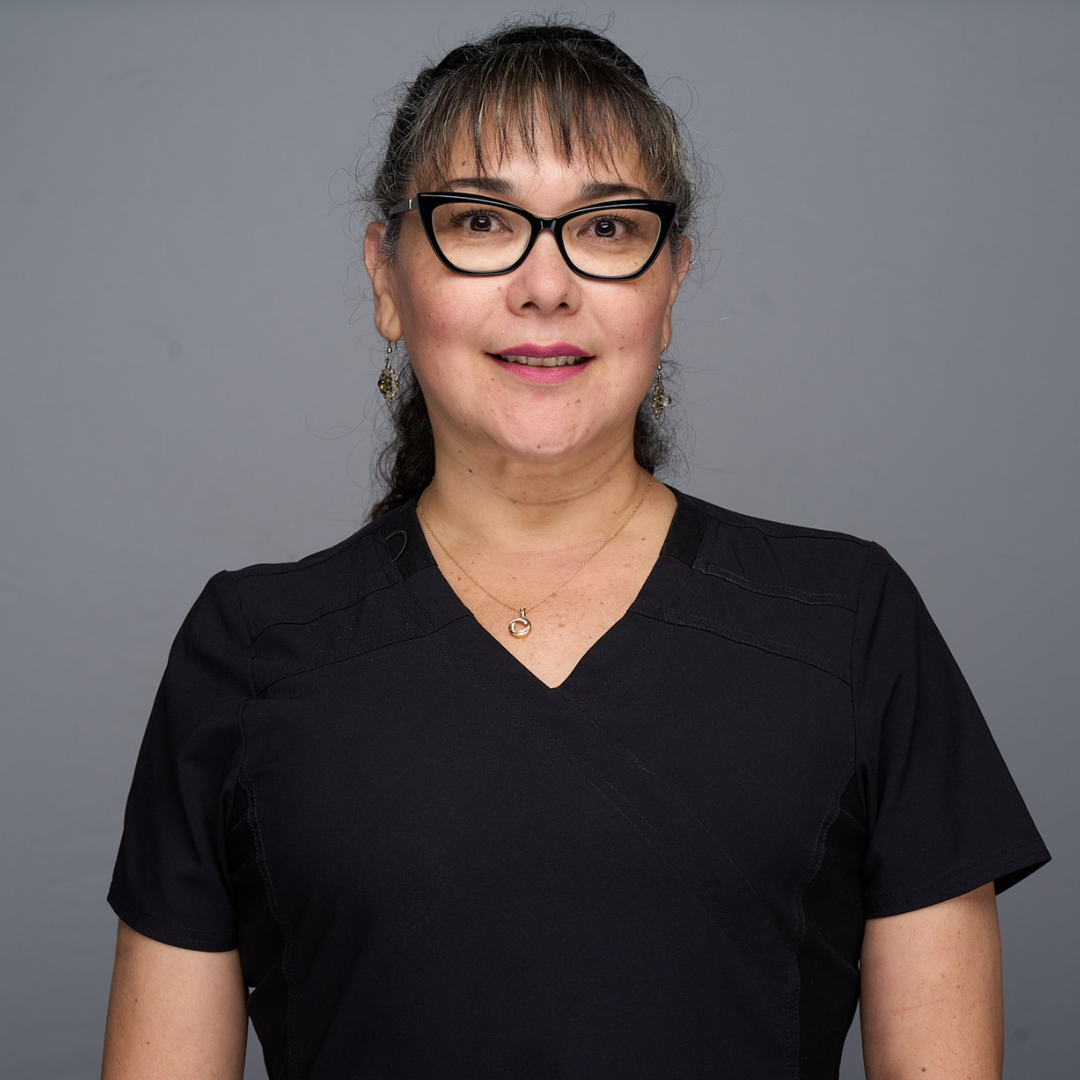 Woman wearing glasses and a black V-neck top against a gray background.