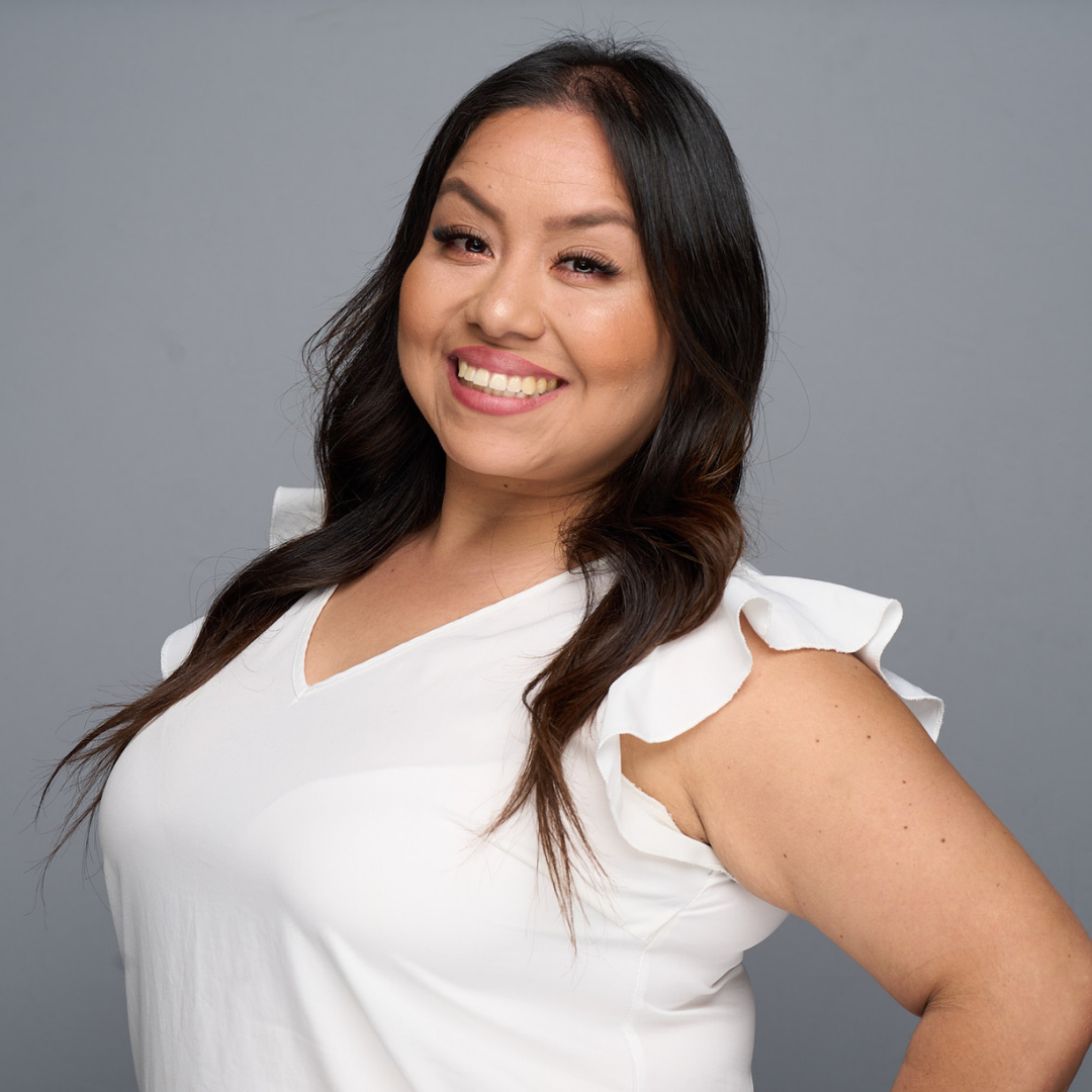 Smiling woman in a white blouse against a gray background