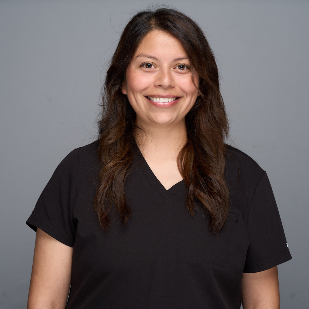 Smiling woman in a black V-neck shirt against a plain gray background