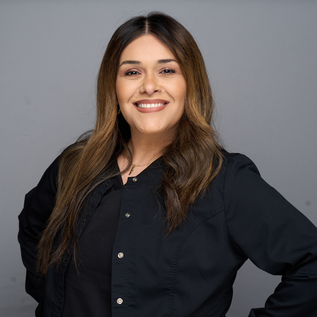 Smiling woman in a black shirt posing against a gray background