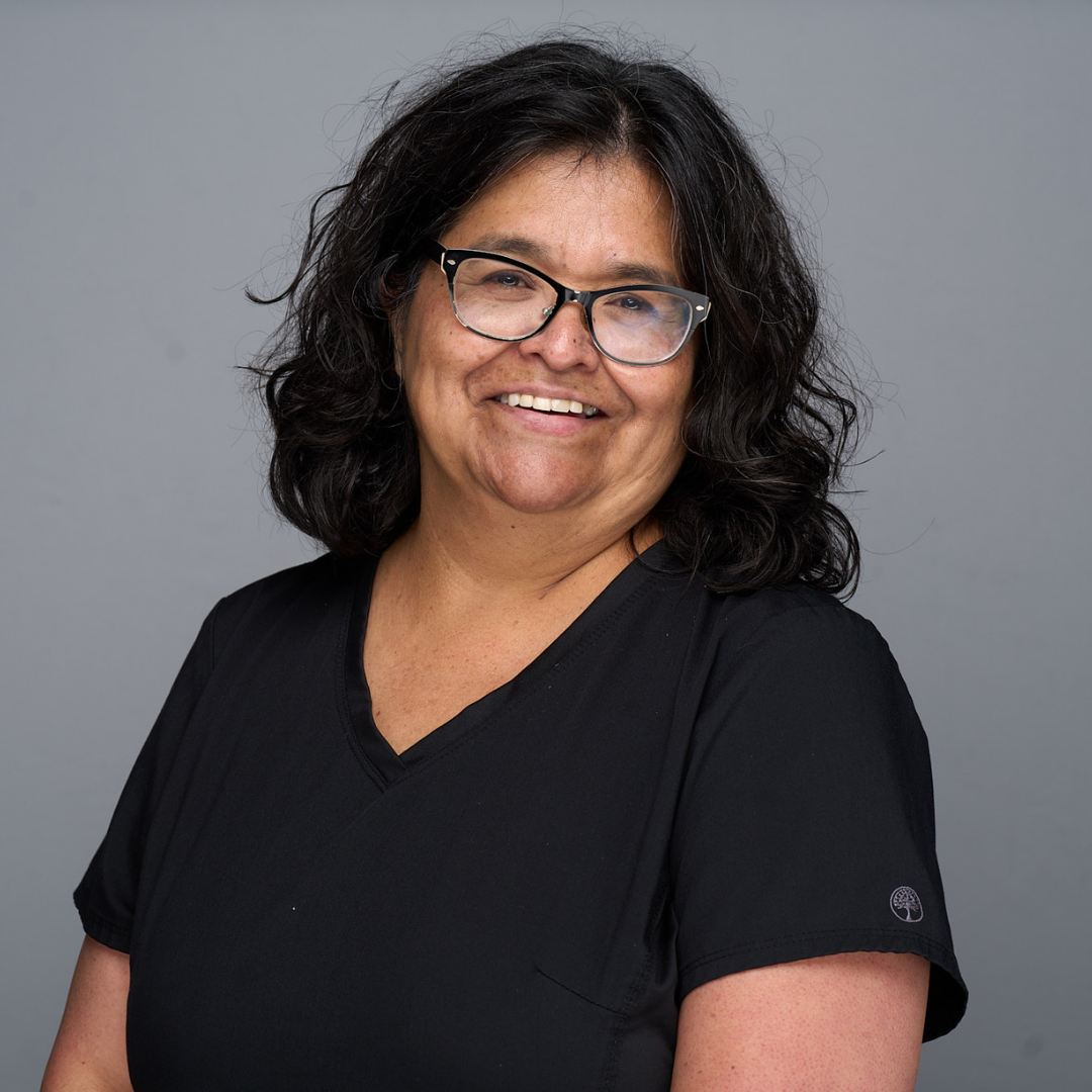 Smiling person in black shirt and glasses against a gray background