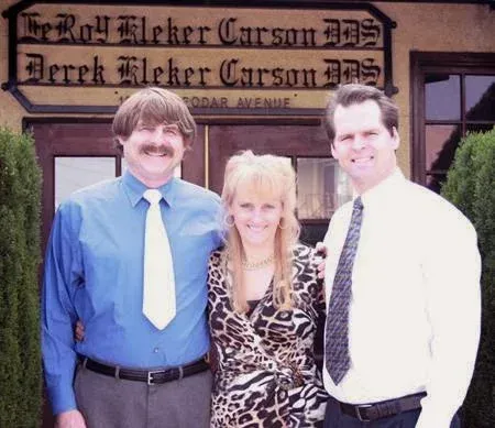 Three people posing outside the Derek Kleker Carson law office sign.