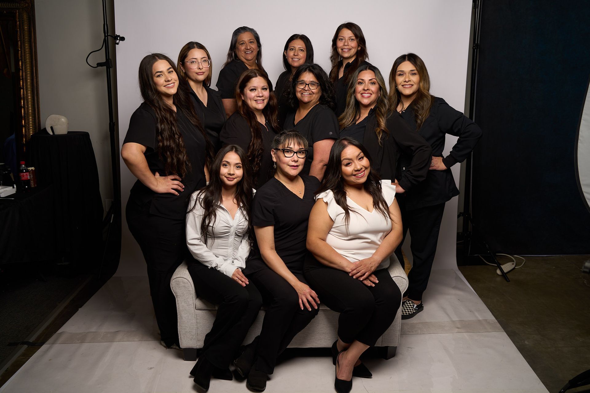 Group of women posing in a studio, dressed in black and white outfits, smiling at the camera.