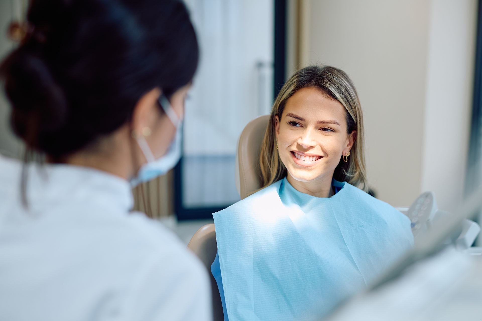 Smiling patient in a dental chair speaking with a dentist in a bright clinic